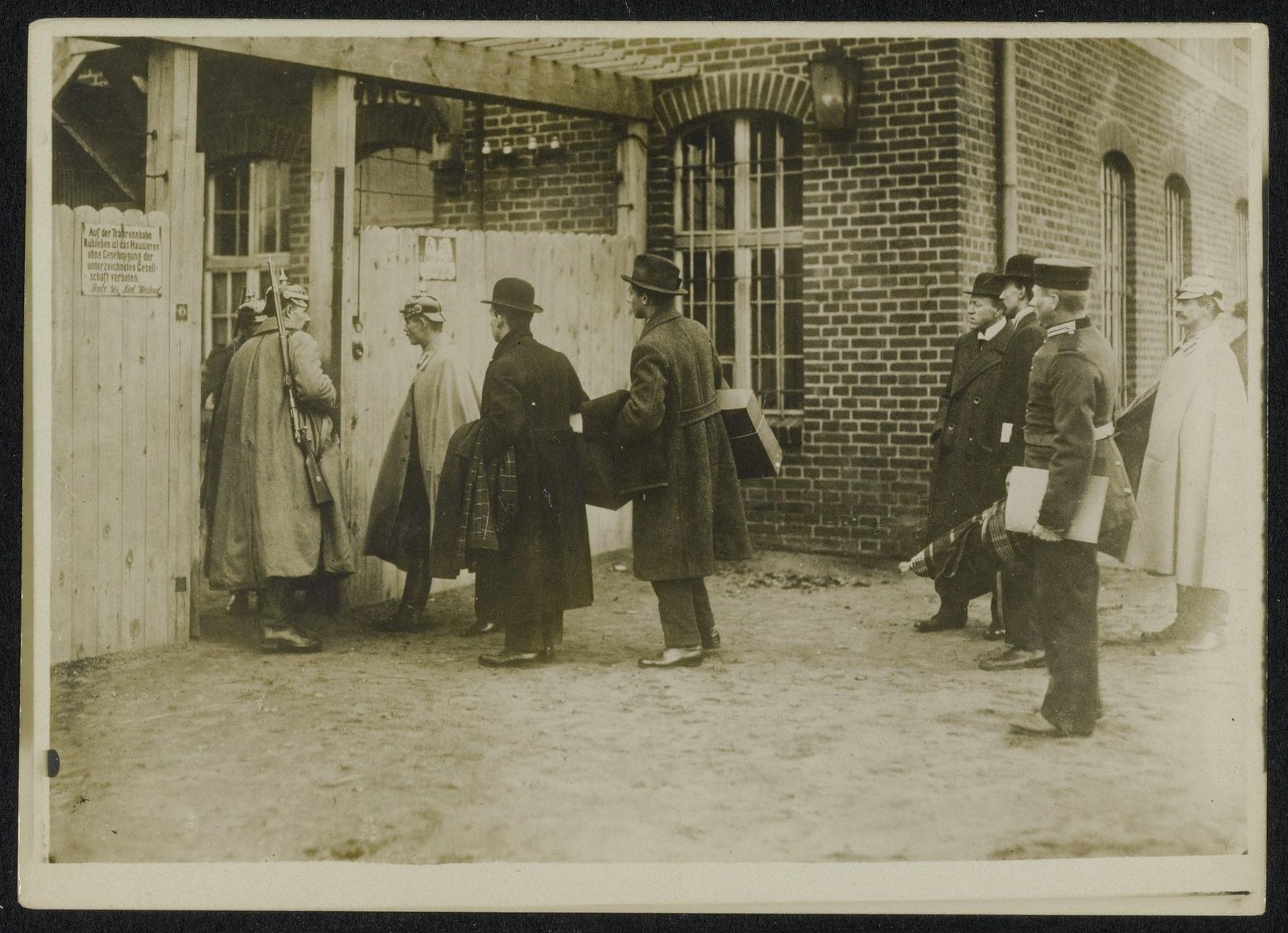 Black-and-white First World War photograph of British civilian men arriving at the Ruhleben racecourse internment site near Berlin under German supervision.