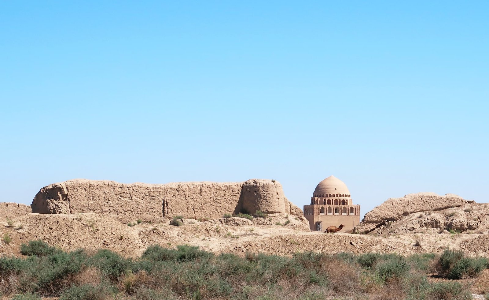 Sultan Sanjar's domed mausoleum rises beyond ruined earthen walls at Ancient Merv in Turkmenistan.