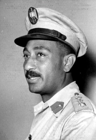 Anwar Sadat in a light military uniform and cap in a 1953 portrait.