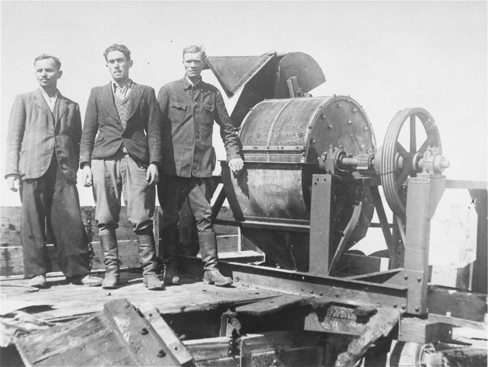 Three Jewish former Sonderkommando 1005 prisoners standing beside evidence-destruction equipment at Janowska after liberation in August 1944.
