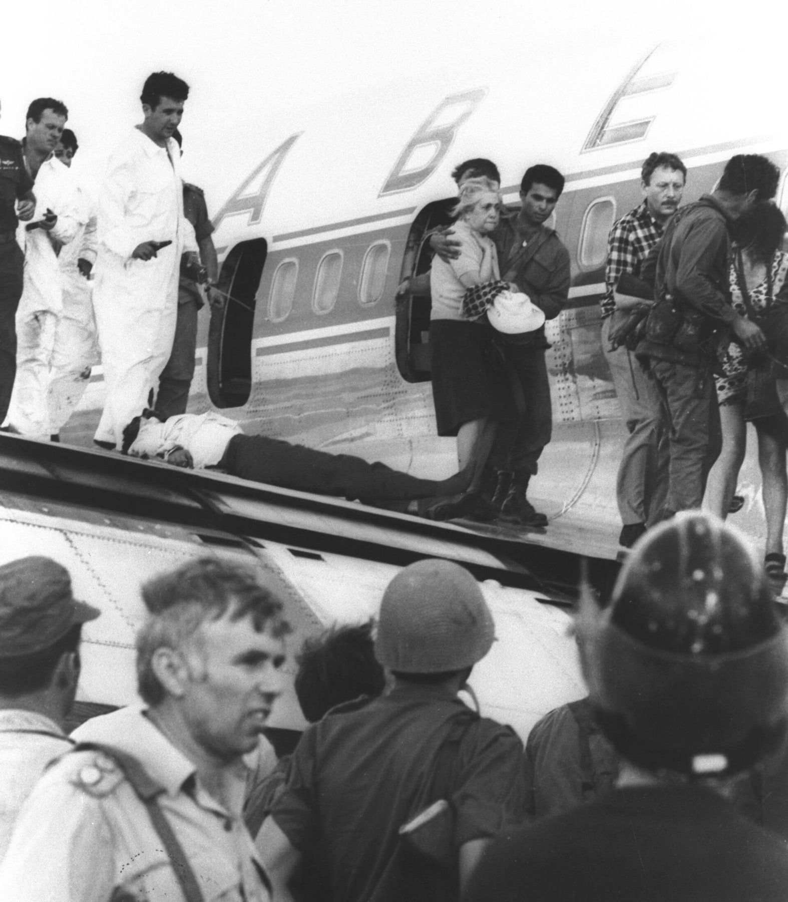 Black-and-white May 1972 photograph beside the hijacked Sabena Boeing 707 at Lod Airport, showing white-overall Israeli commandos and people being helped from the aircraft.