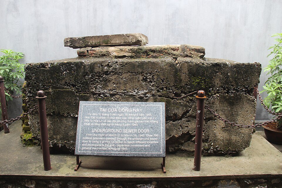 Preserved concrete sewer opening at Hỏa Lò Prison, displayed as the route used by political prisoners during the March 1945 mass escape.
